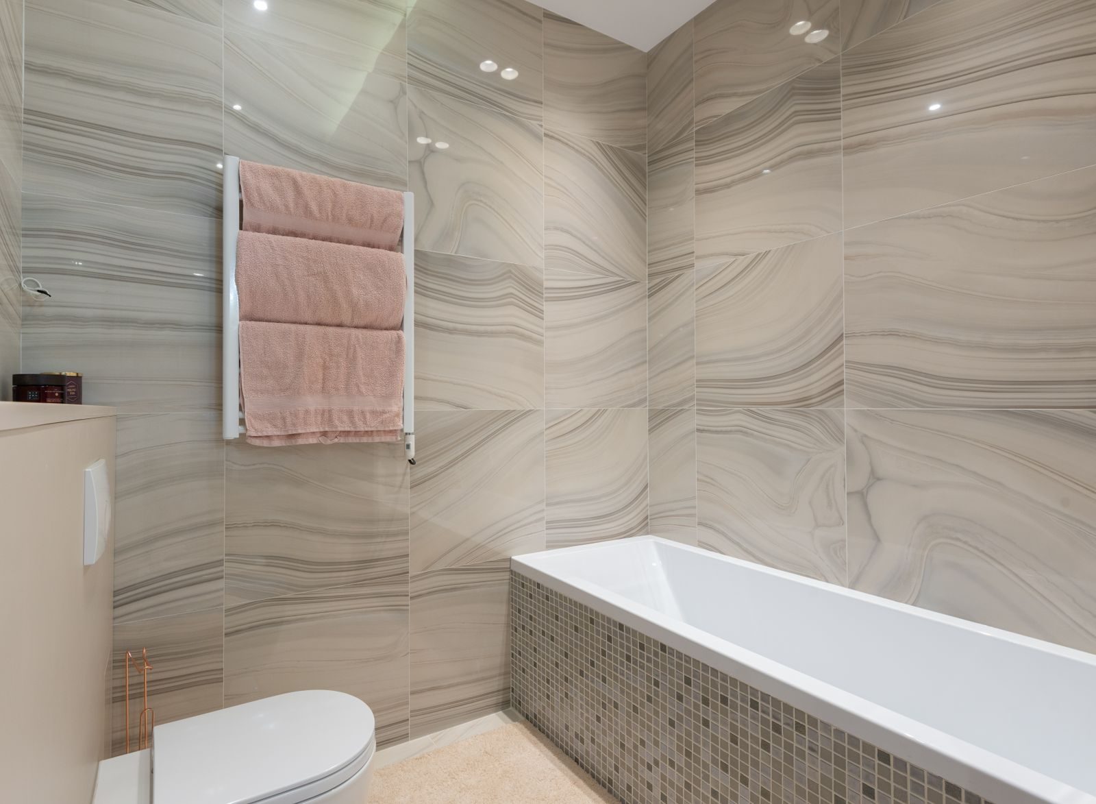 A renovated bathroom with bath and marble-effect tiling
