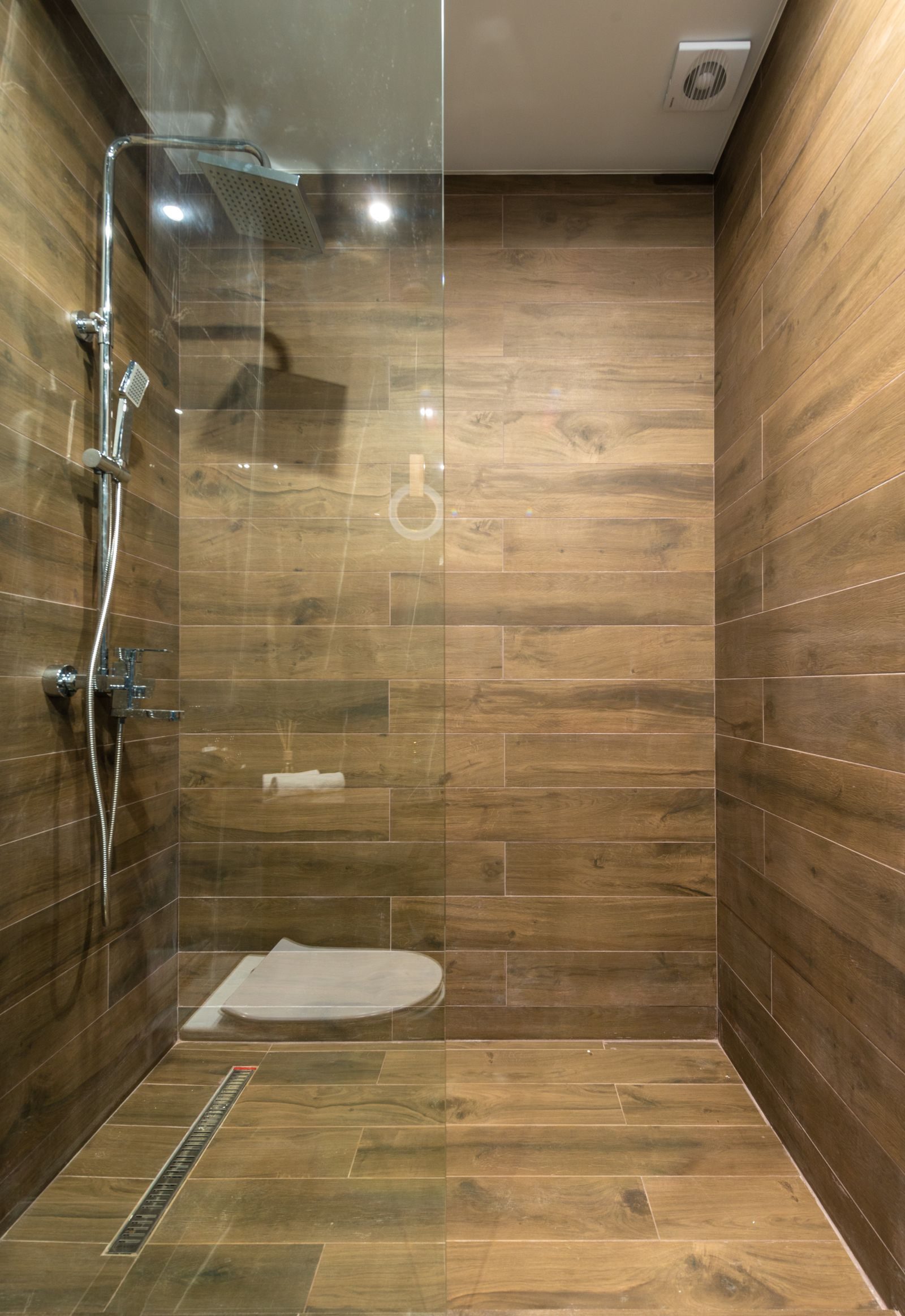 A wood-effect wet room with linear drain and glass panel